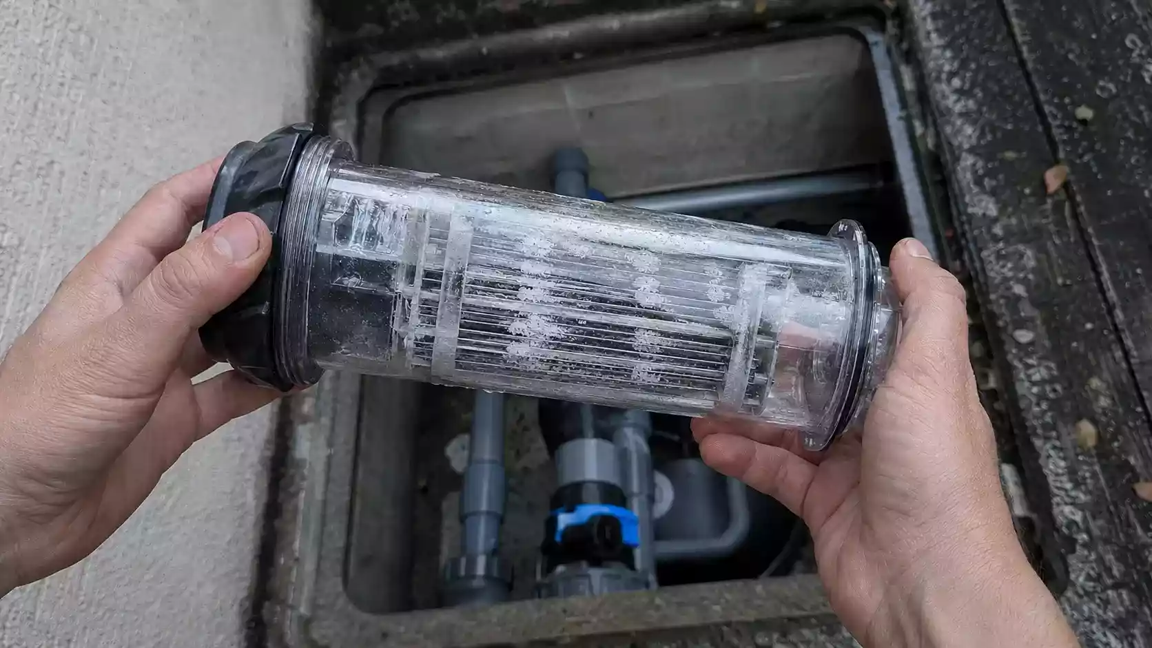 Cellule d'électrolyseur au sel démontée tenue en main au-dessus du local technique avant hivernage