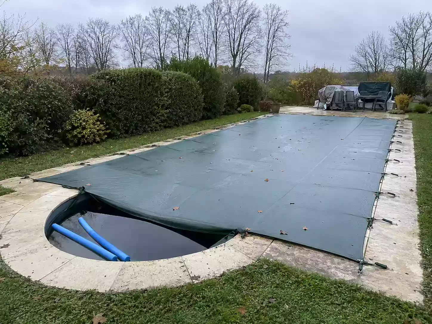 Piscine couverte pour l'hiver avec bâche tendue et flotteurs d'hivernage en diagonale