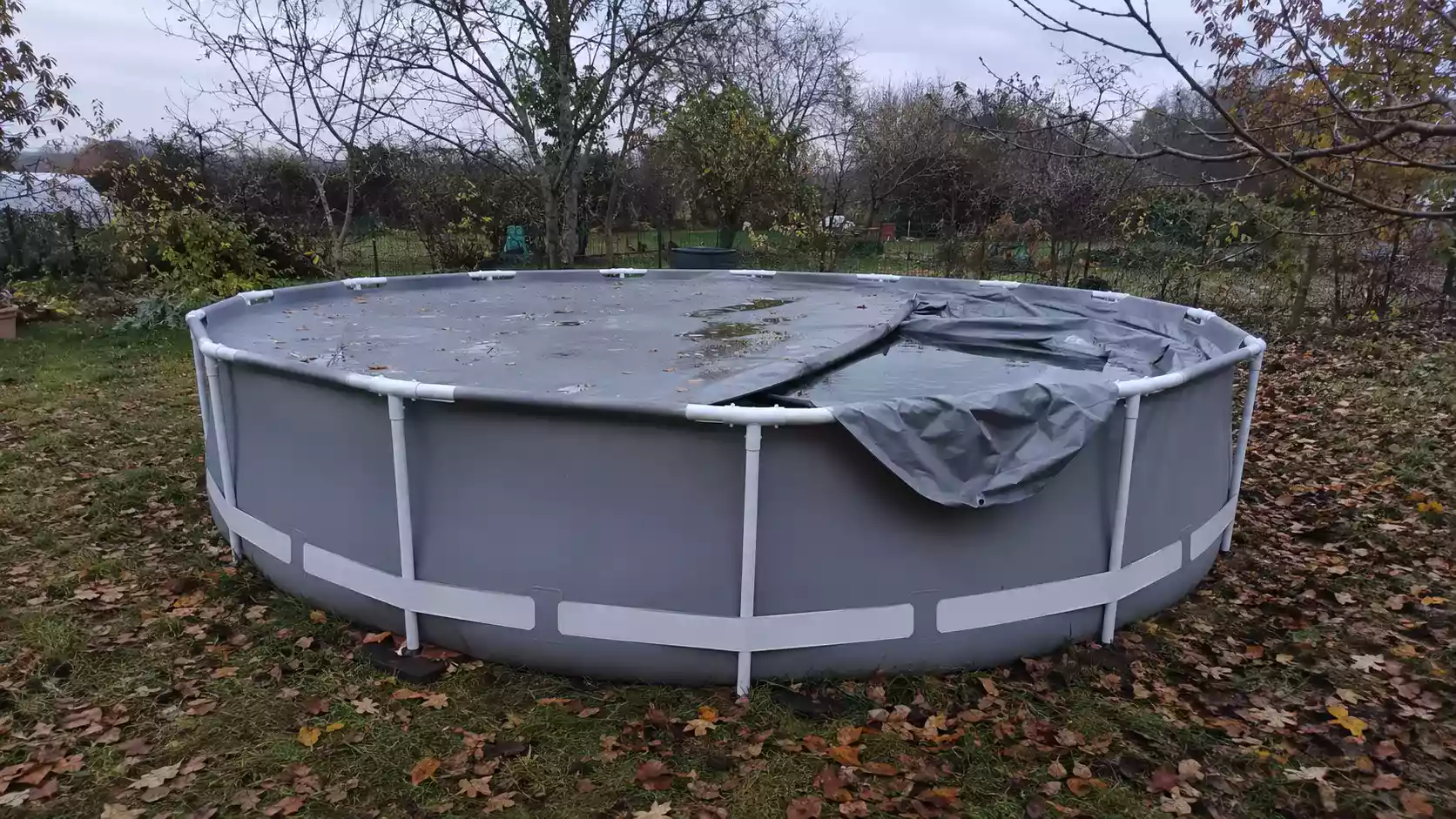 Piscine tubulaire hors sol sous bâche d'hivernage dans un jardin en automne