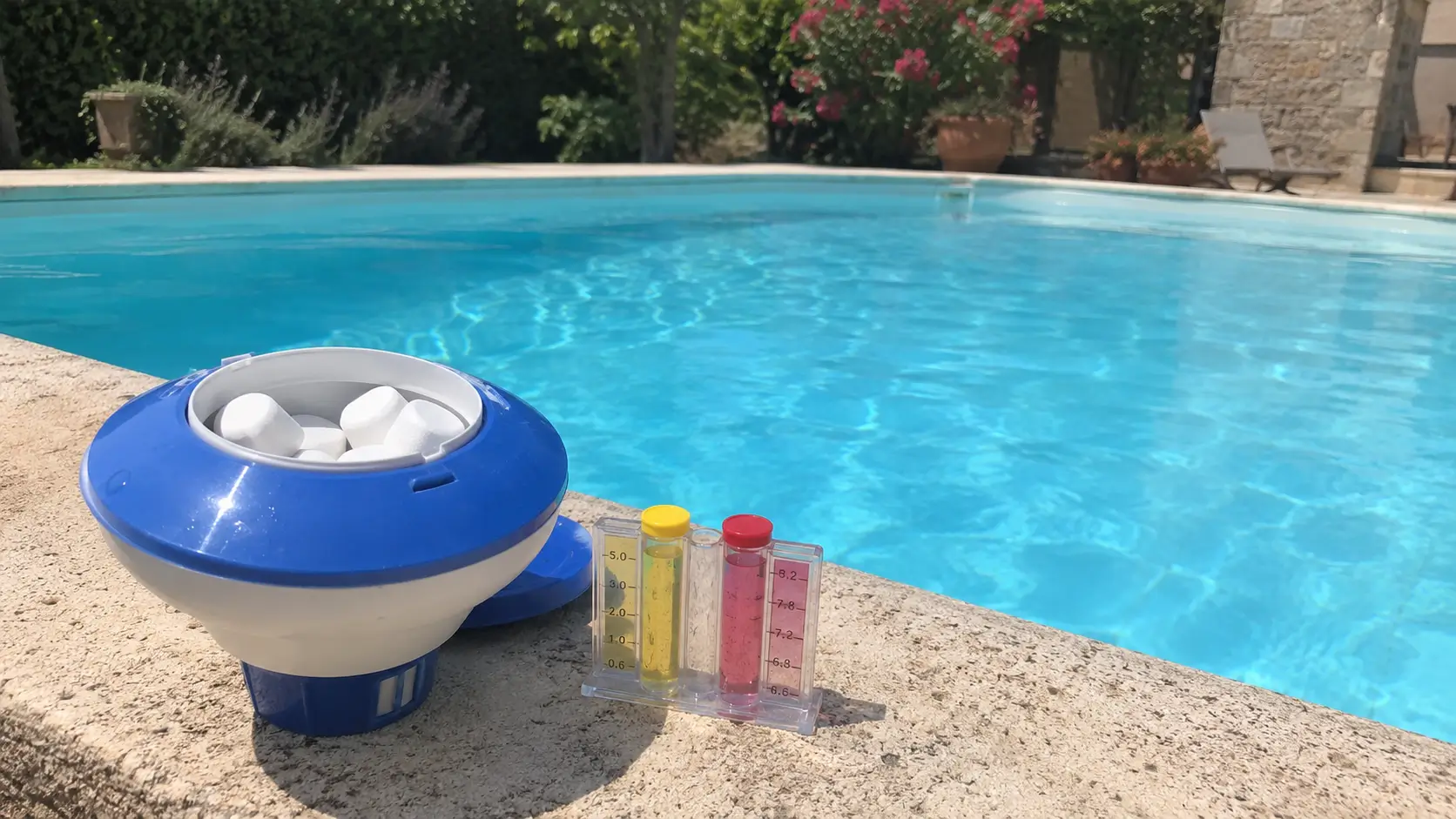 Doseur flottant plein de galets de chlore et testeur au bord d'une piscine, surdosage de chlore