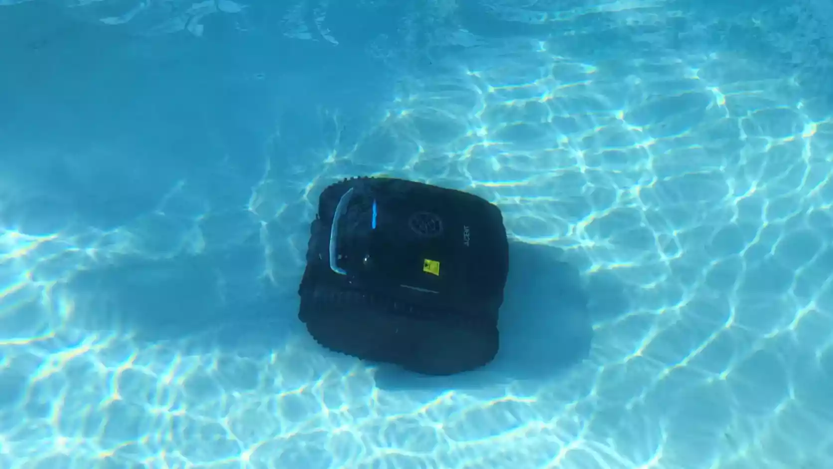 Wybot C2 en nettoyage du fond d'une piscine à l'eau claire avec reflets de soleil