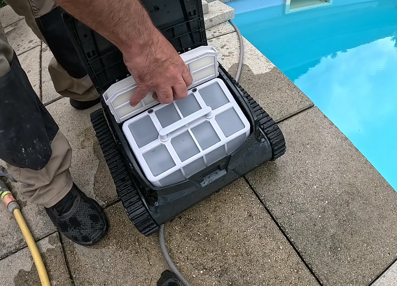 Panier filtrant et cartouche mousse ultra-fine du Wybot S2 retirés à la main au bord de la piscine
