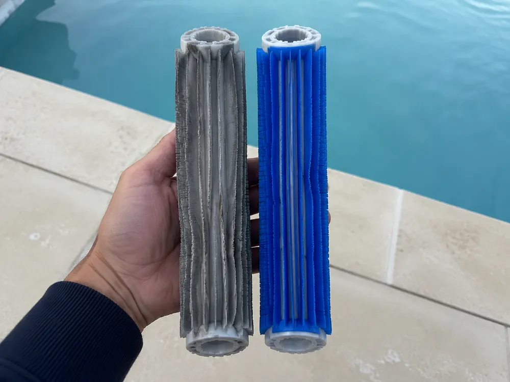 Deux brosses de robot de piscine tenues côte à côte au dessus d'un bassin, celle de gauche grise aux lamelles affaissées, celle de droite bleue aux lamelles droites