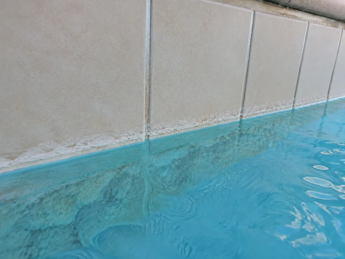 Croûte de calcaire blanche formée sur les carreaux de la ligne d'eau d'une piscine au pH trop haut