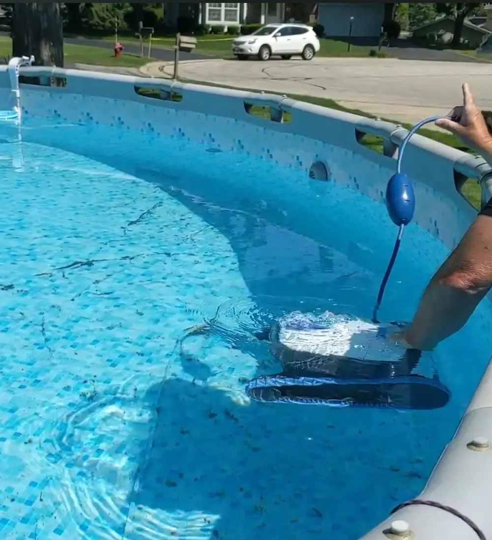 Robot Dolphin S100 à la surface de l'eau au moment de la mise à l'eau, avec le flotteur positionné sur son câble