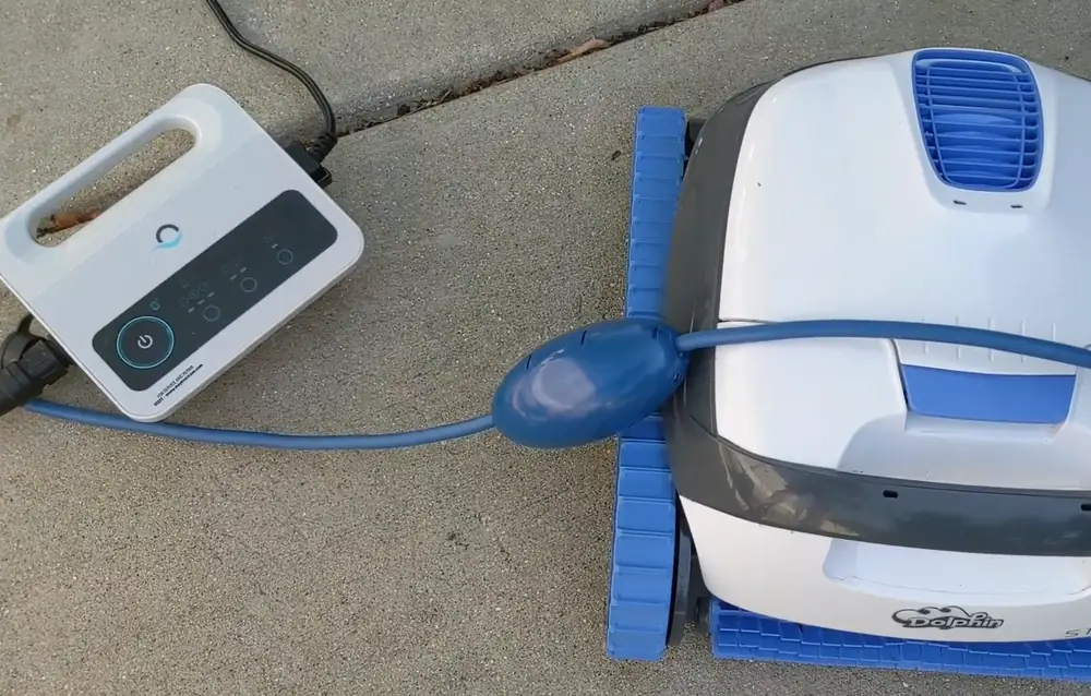 Robot de piscine Dolphin S100 vu de profil, avec ses chenilles bleues et sa poignée de transport