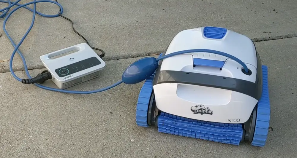 Robot Dolphin S100 posé au bord du bassin à côté de son boîtier d'alimentation