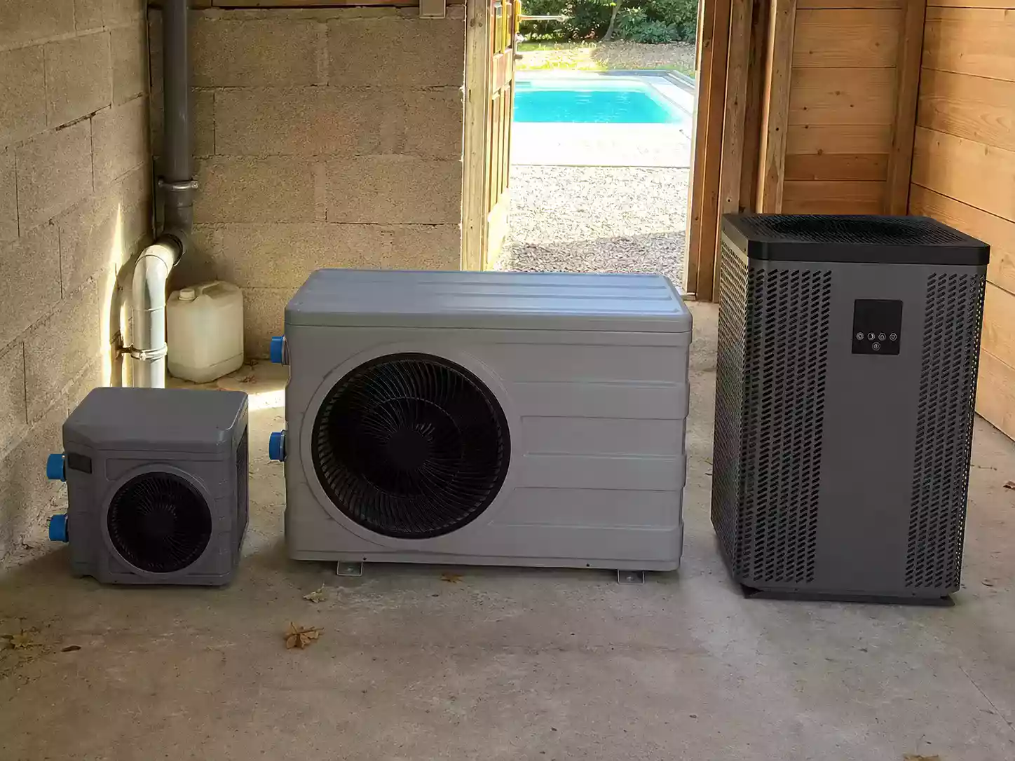 Trois pompes à chaleur de piscine comparées côte à côte dans un local technique avant installation
