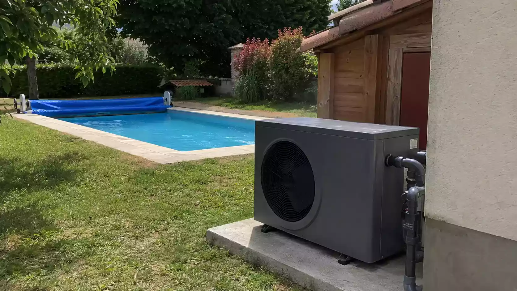 Pompe à chaleur de piscine en fonctionnement au bord d'un bassin enterré dans un jardin en France