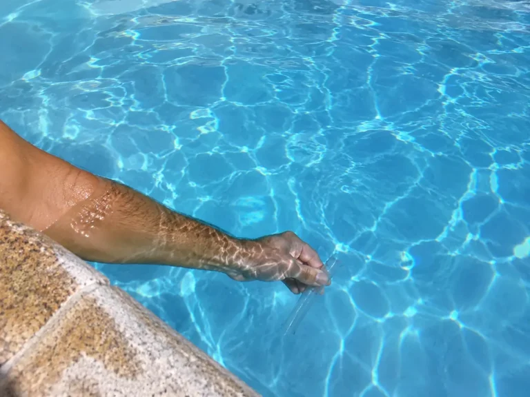 Bras plongé dans l'eau d'une piscine tenant un tube de prélèvement à 40 cm sous la surface
