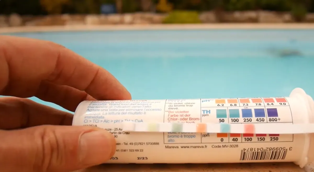 Bandelette de test comparée à l'échelle de couleurs du TH, piscine en arrière-plan