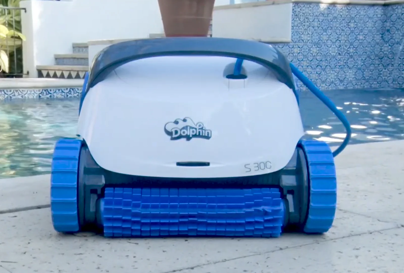 Robot de piscine Dolphin S300 vu de face sur une terrasse, brosse bleue à l'avant