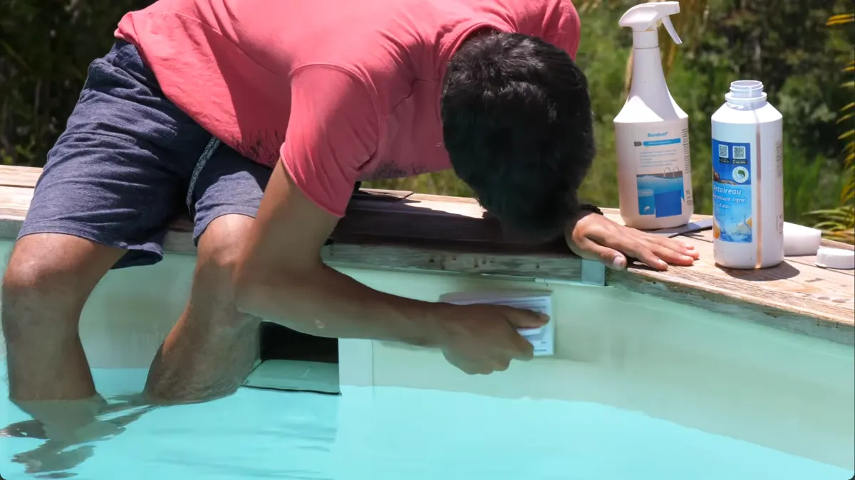 Nettoyage de la ligne d'eau d'un liner à l'éponge, produits posés sur la margelle