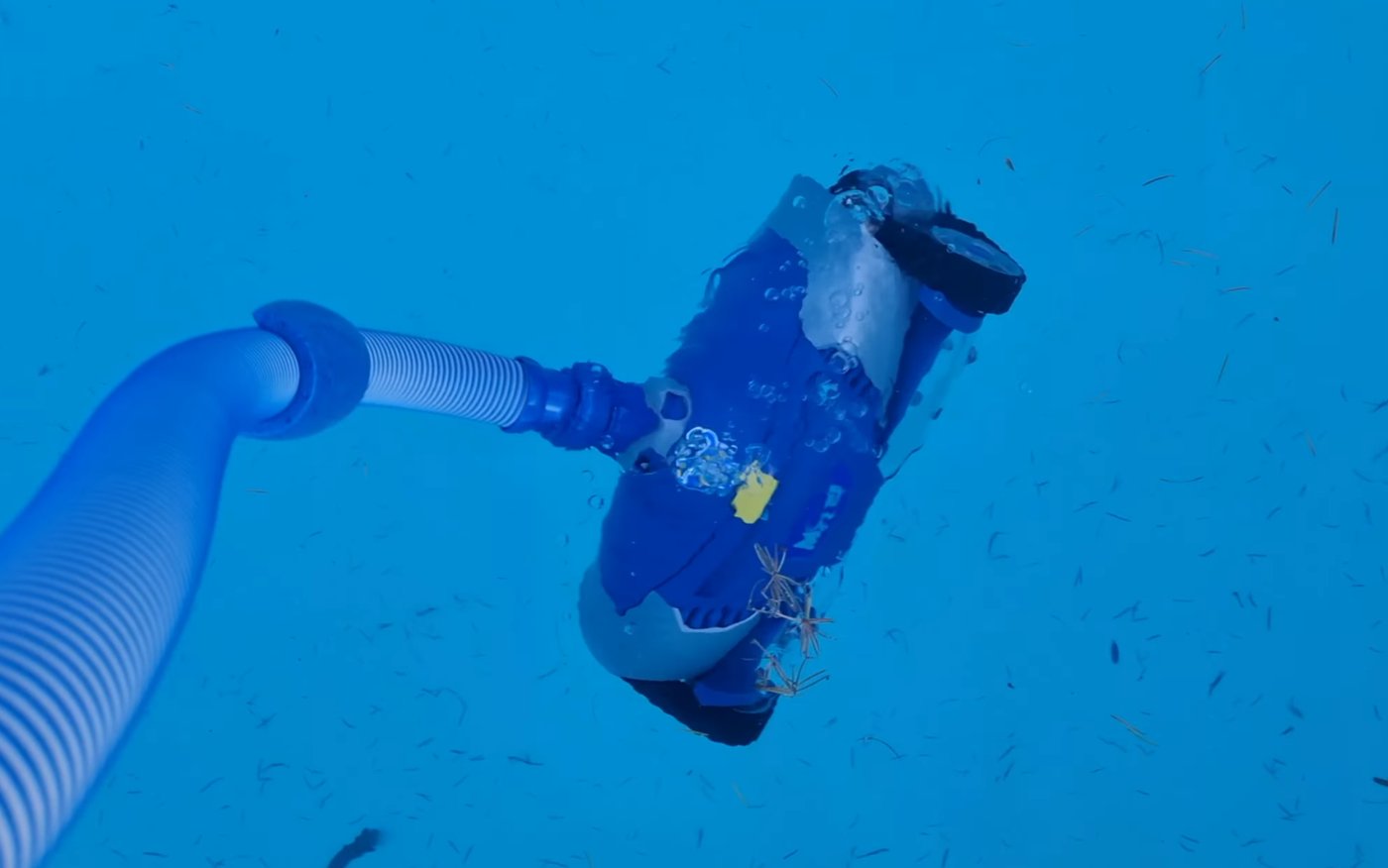 Zodiac MX9 au fond d'une piscine, relié à la prise balai par son tuyau
